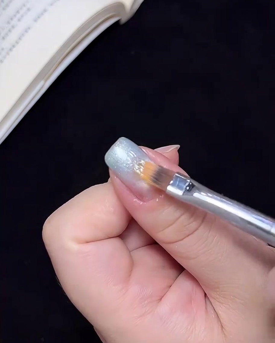 清潔なブラシを使って、ブルーのジェルを中心に向けてぼかし、オンブレ効果を作っている様子。