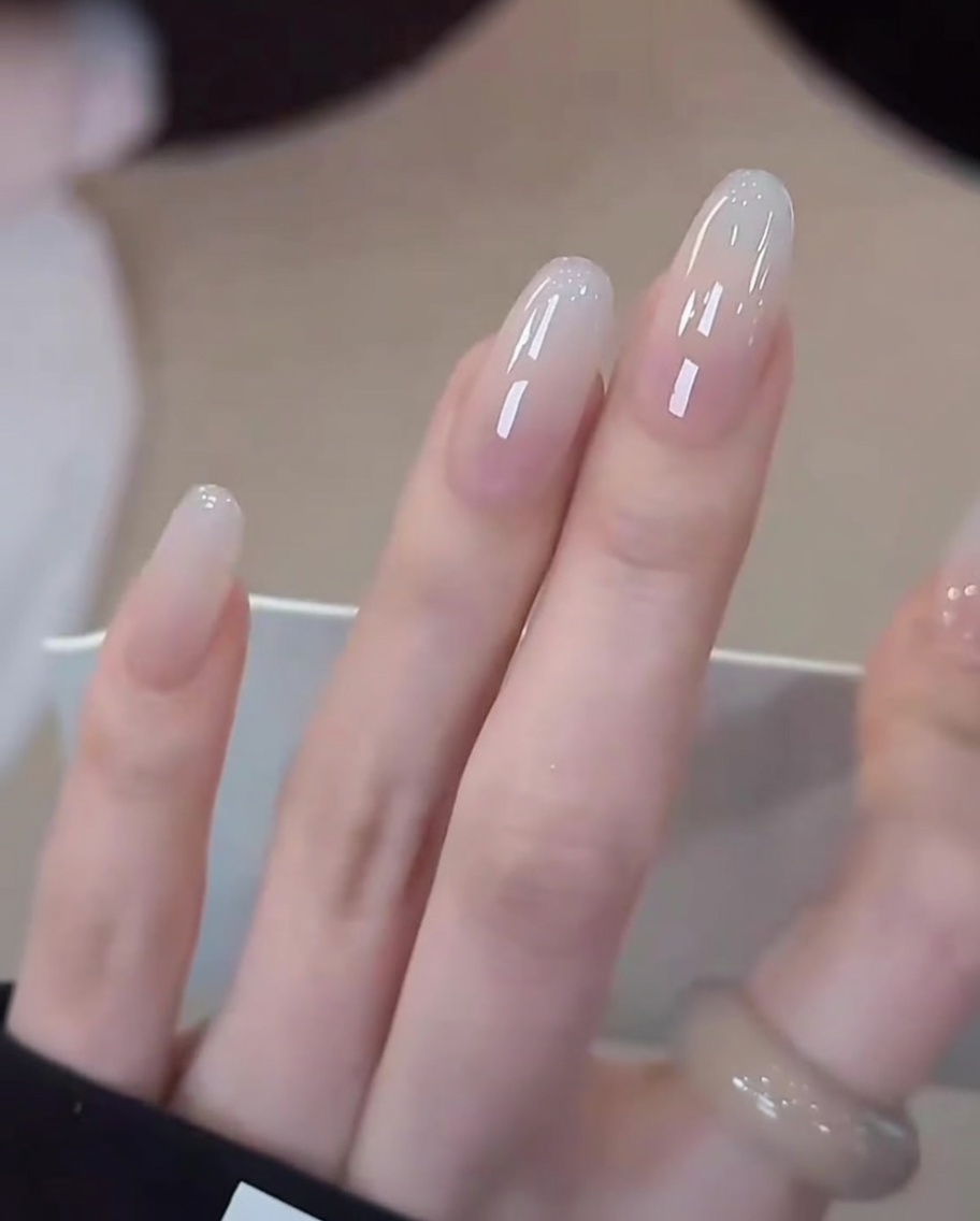 完成したミルキーホワイトのグラデーションネイルをUV/LEDランプで最終硬化させている様子。