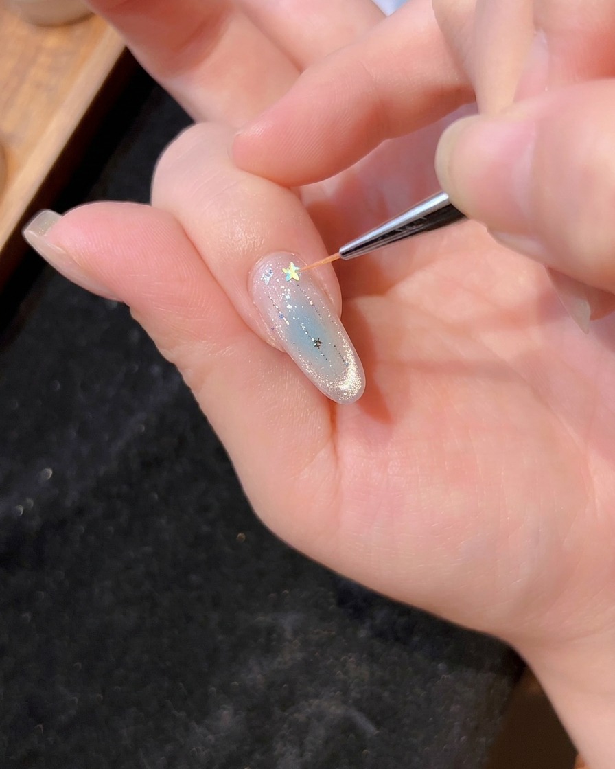 ピンセットやドットペンで、星の形のグリッターをジェルに乗せている様子。