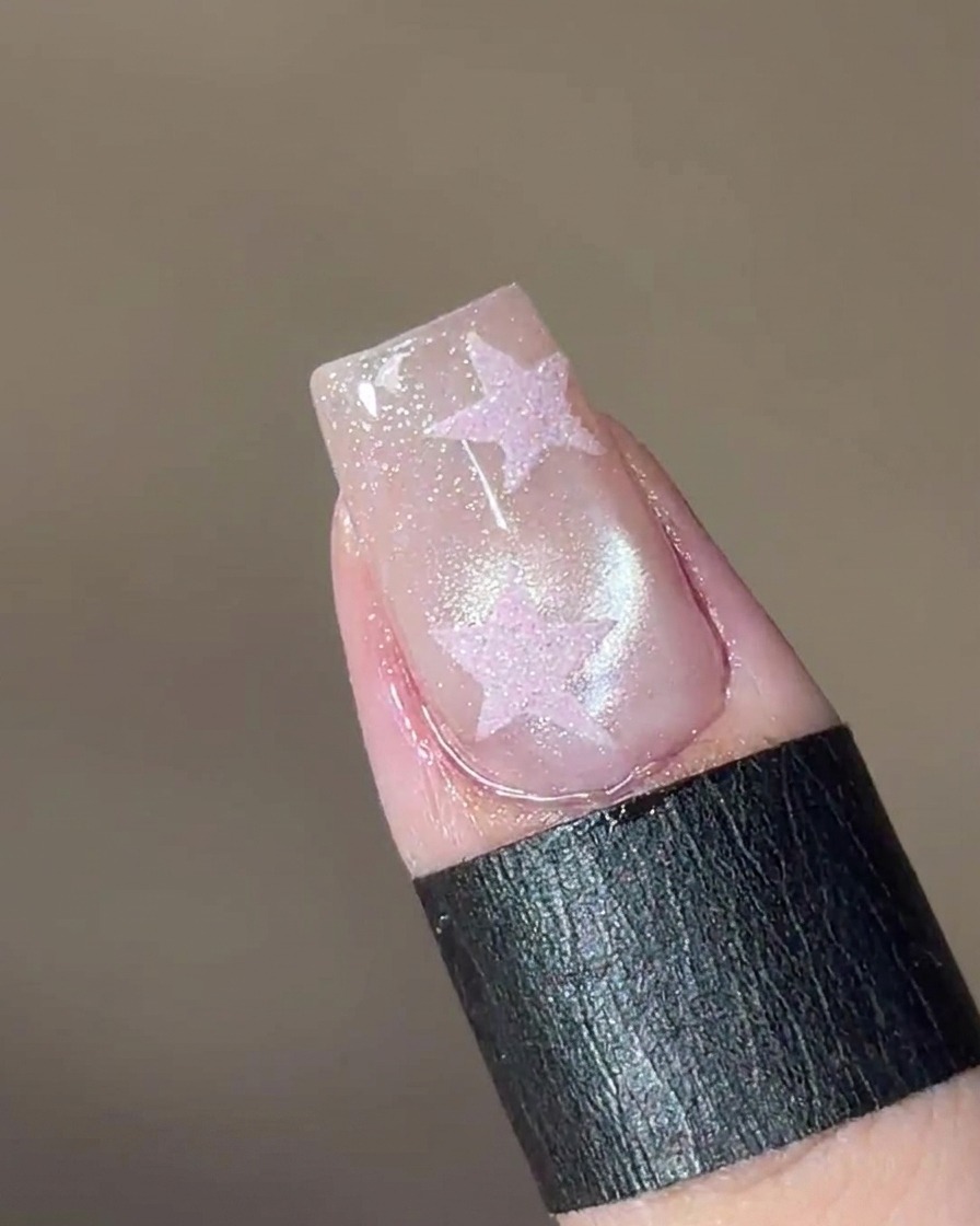 磁石を爪の上にかざし、粒子を寄せてガラスビーズのような模様を作っている様子。