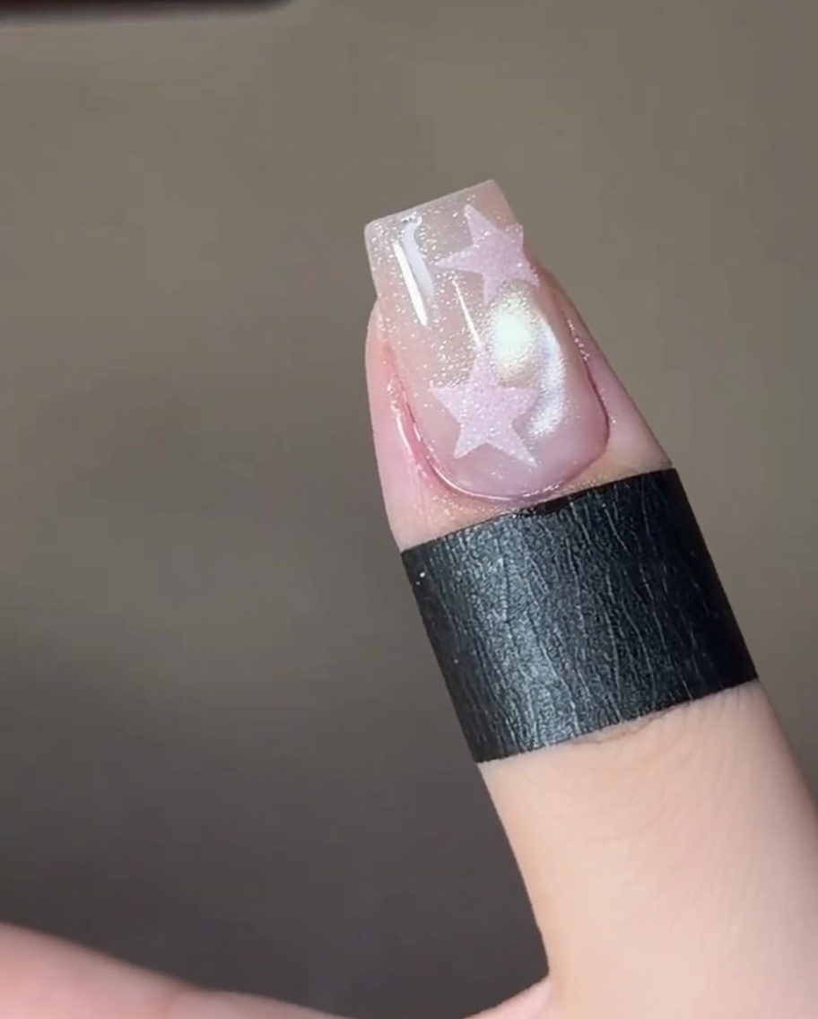 ピンセットを使って星型のステンシルステッカーを爪の上に貼っている様子。