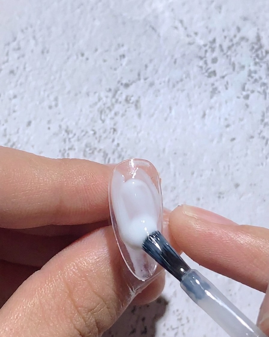 清潔なブラシでウェットな白ジェルをぼかし、ソフトフォーカスなベースを作っている様子。