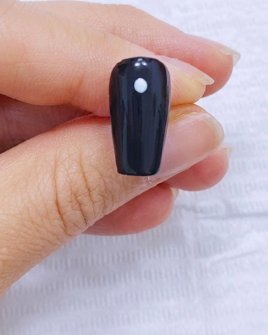 黒いネイルの中心にある白いドットの周りに、4つのドットを円状に配置した画像。