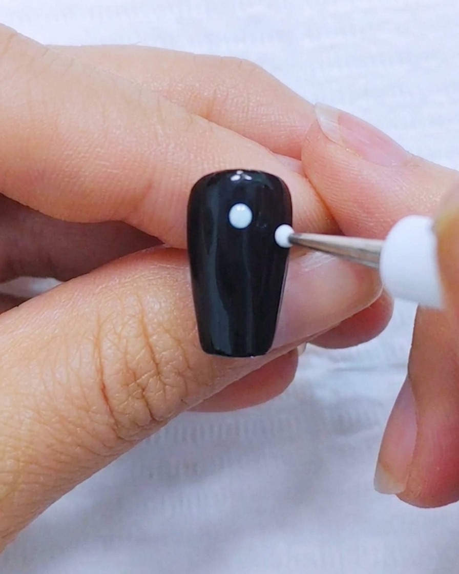 黒いネイルの背景に5つの白いドットが対称に配置されている様子。