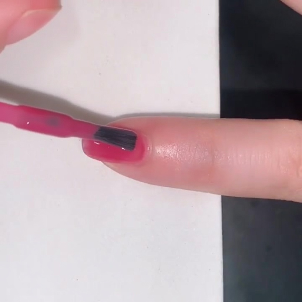 透け感のあるピンクのジェリーカラーを爪に塗っているブラシの様子。