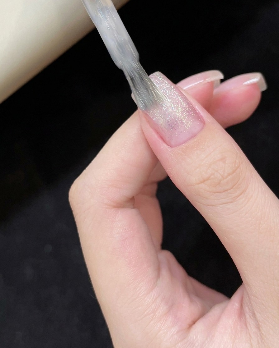 爪の表面にシアーホワイトのキャッツアイジェルを塗布する様子。