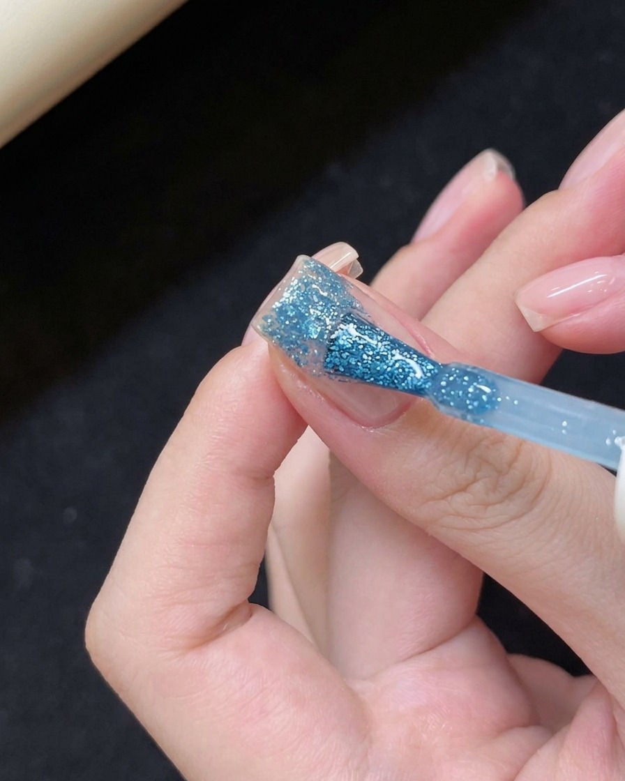 爪の先端にブルー系のジェルを塗布する様子。