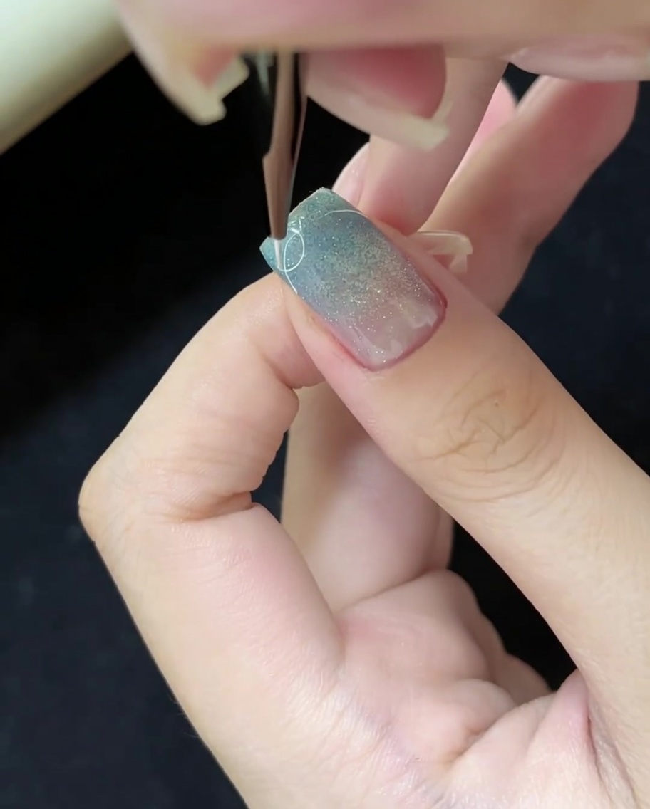 細いライナーブラシを使って、爪の表面に細かい白い線を描く様子。