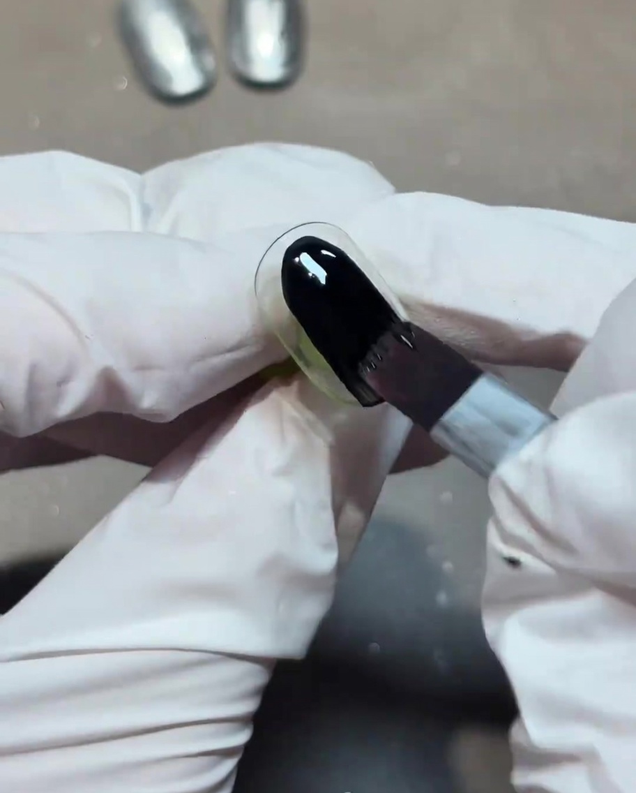黒のジェルネイルを爪全体に塗布している様子