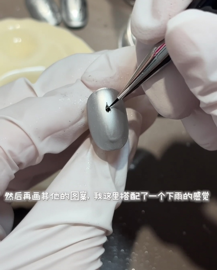 細筆でマットグレーのネイルの上に、水の波紋を表現する円形の模様を描いている様子