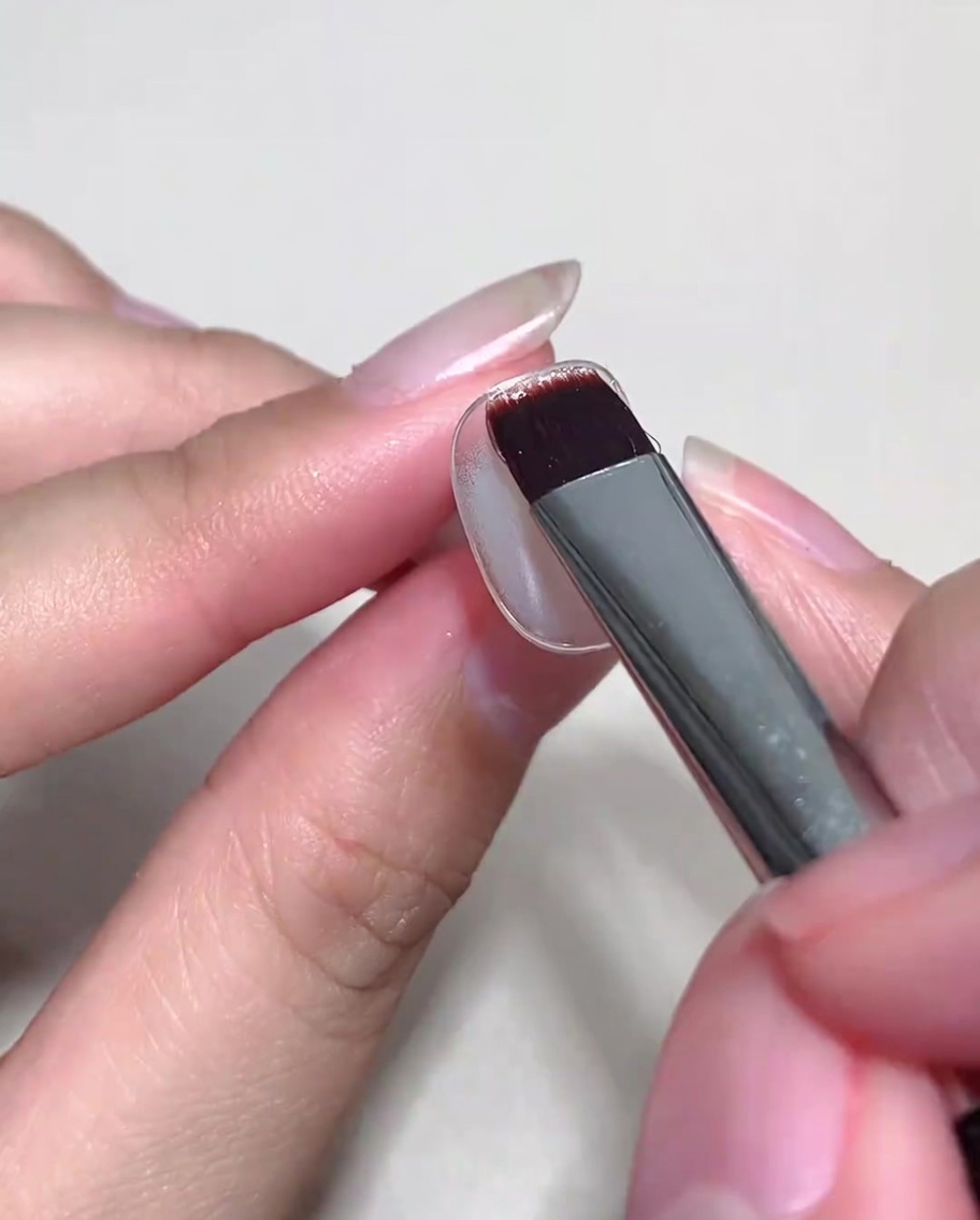 硬化済みのベースの上から、ヌードカラーのキャットアイジェルを塗布している様子。