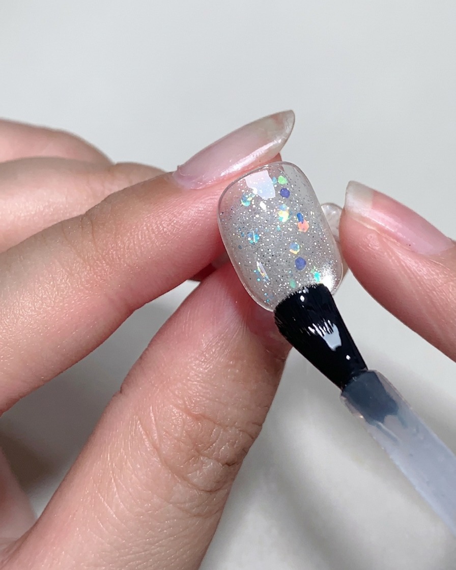 硬化したキャットアイの上に、クリアなブルーミングジェルを薄く塗っている様子。