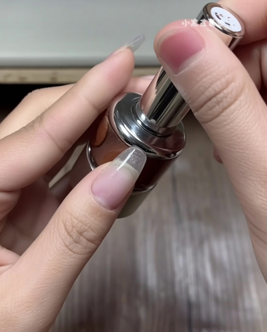 ピンセットを使って、白いガイドシートからカーブしたフレンチチップシールを選んでいる手。