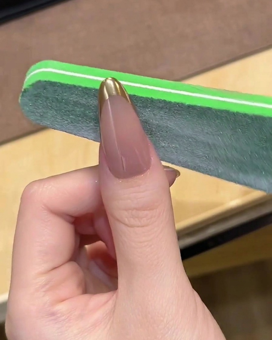 ネイルファイルを使って、クロムフレンチの先端を優しく削って整えている様子。