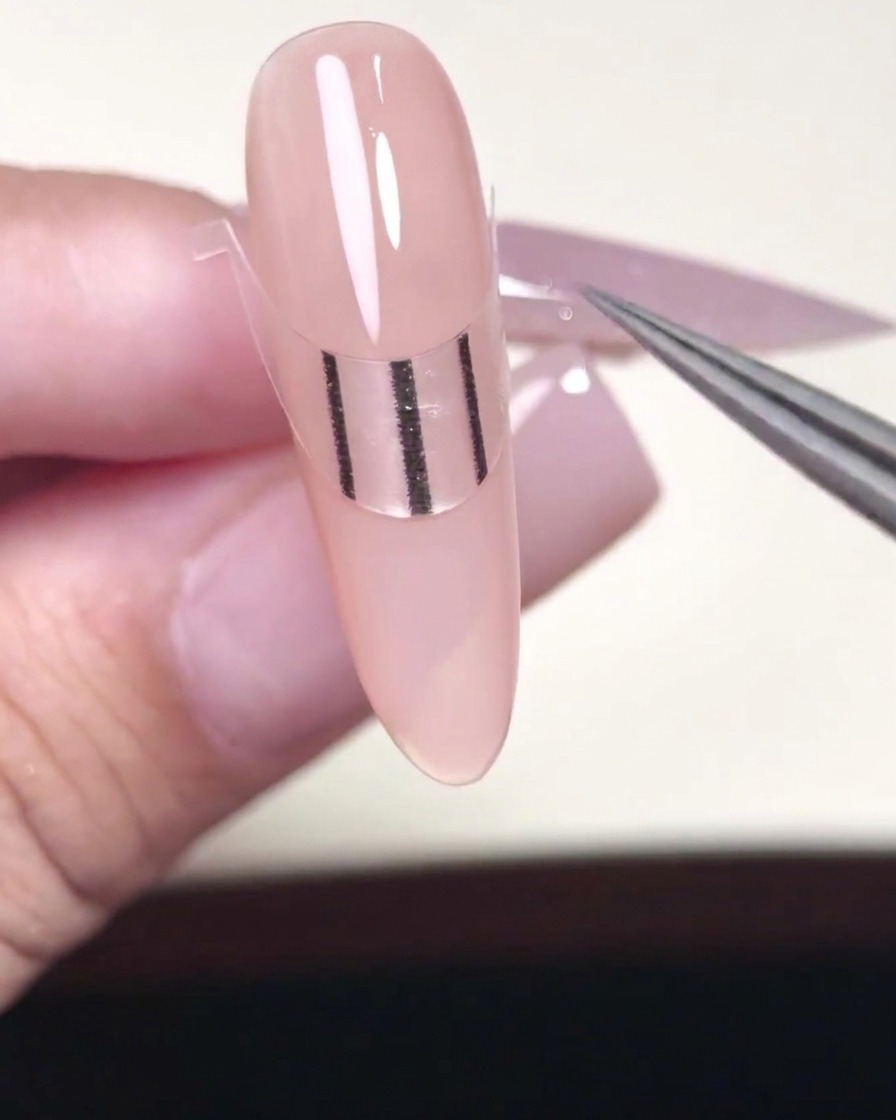 金属製のプッシャーで、フレンチシールが爪にしっかり付くように端を押さえている様子。
