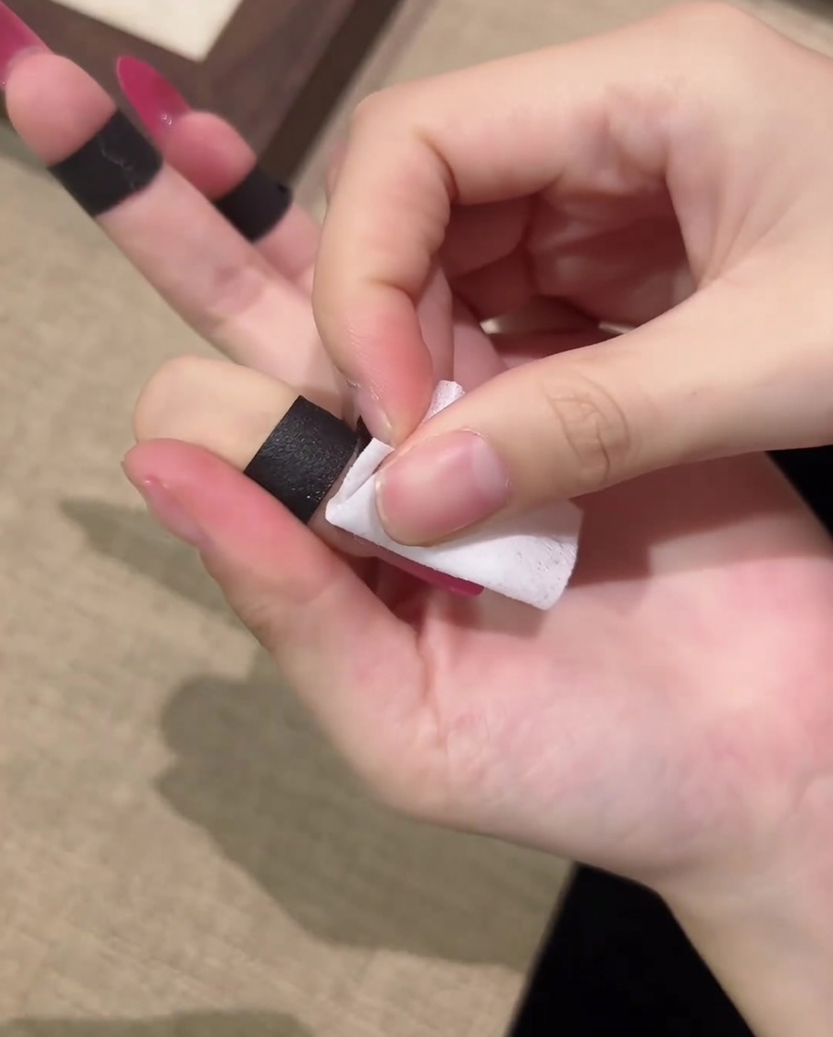 リントフリーコットンで爪の表面のベタつきを拭き取っている様子