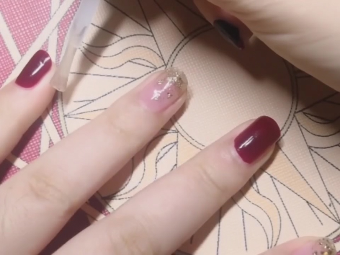 真っ赤なネイルに透明なトップジェルを塗っている様子。