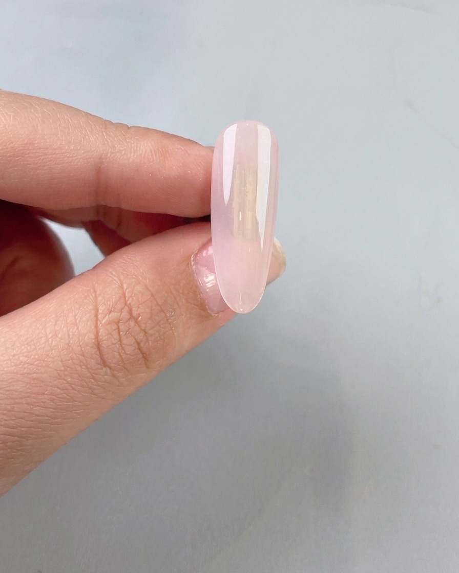 透明感のある少しミルキーなジェイドカラーのベースジェルを自爪に塗っている様子。