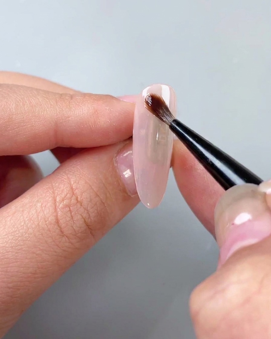 ベースコートの上に透明な水彩ブルーミングジェルを筆で塗布している様子。