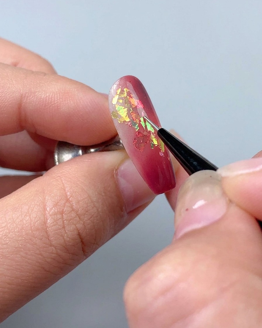 細いライナーブラシを使い、ネイルにスカルプチュアジェルで装飾的な細いラインを描いている様子。