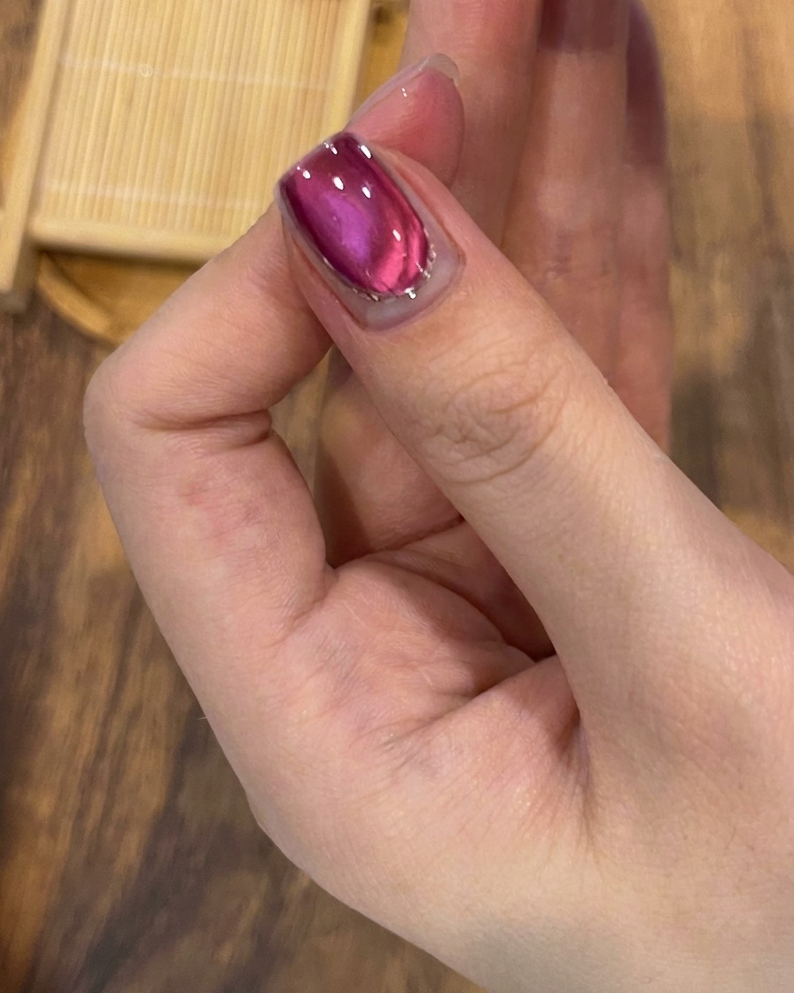 完成したキャッツアイとラメのデザインの上に、透明でツヤのあるトップコートを塗っているブラシ。