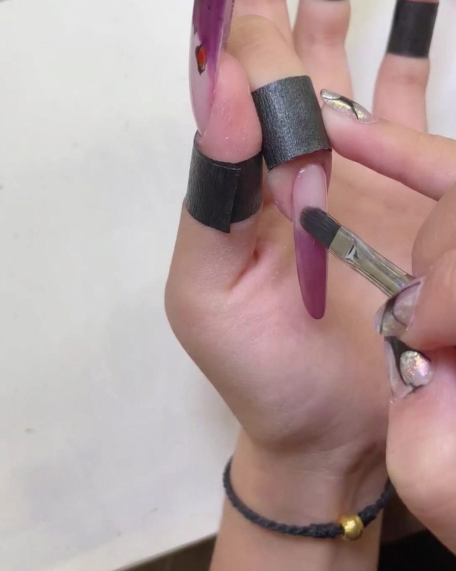 綺麗なブラシを使って、赤いキャットアイジェルのフレンチラインの輪郭を整えている様子。