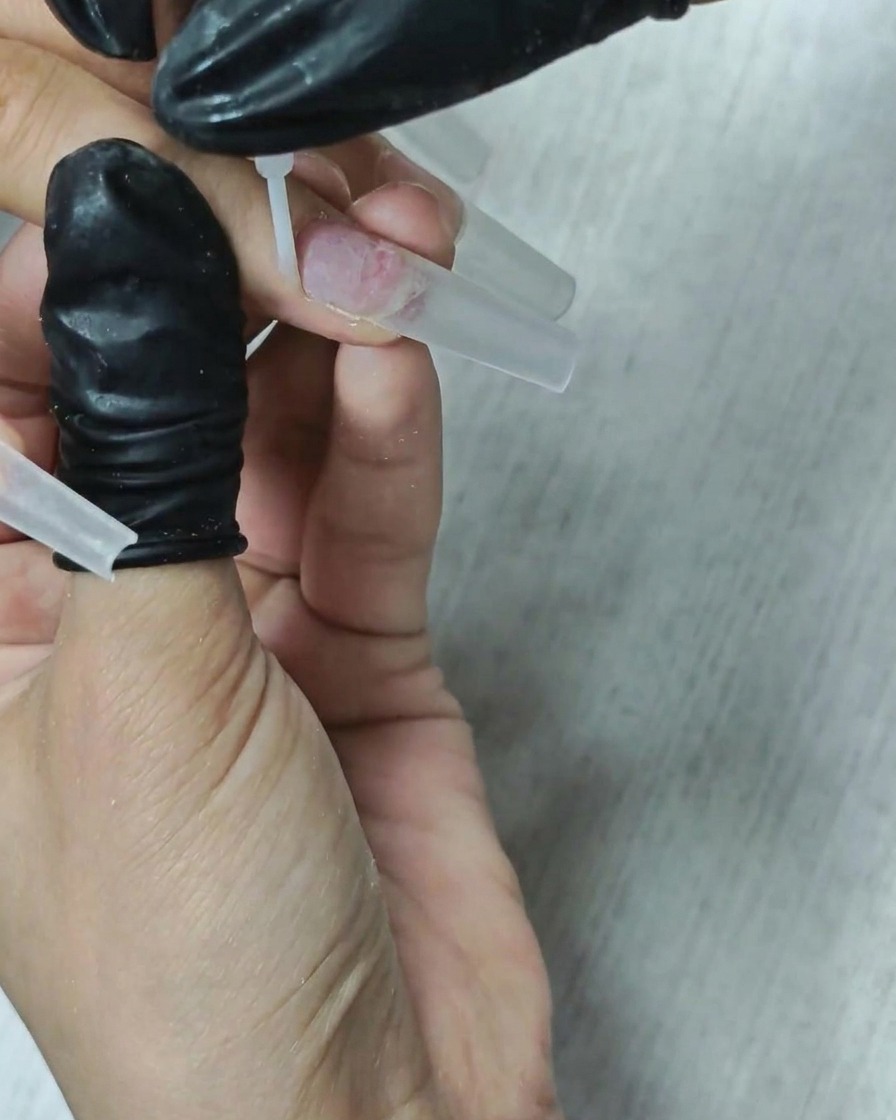 筆を使って、自爪にクリアなディハイドレーター液を塗布している様子。