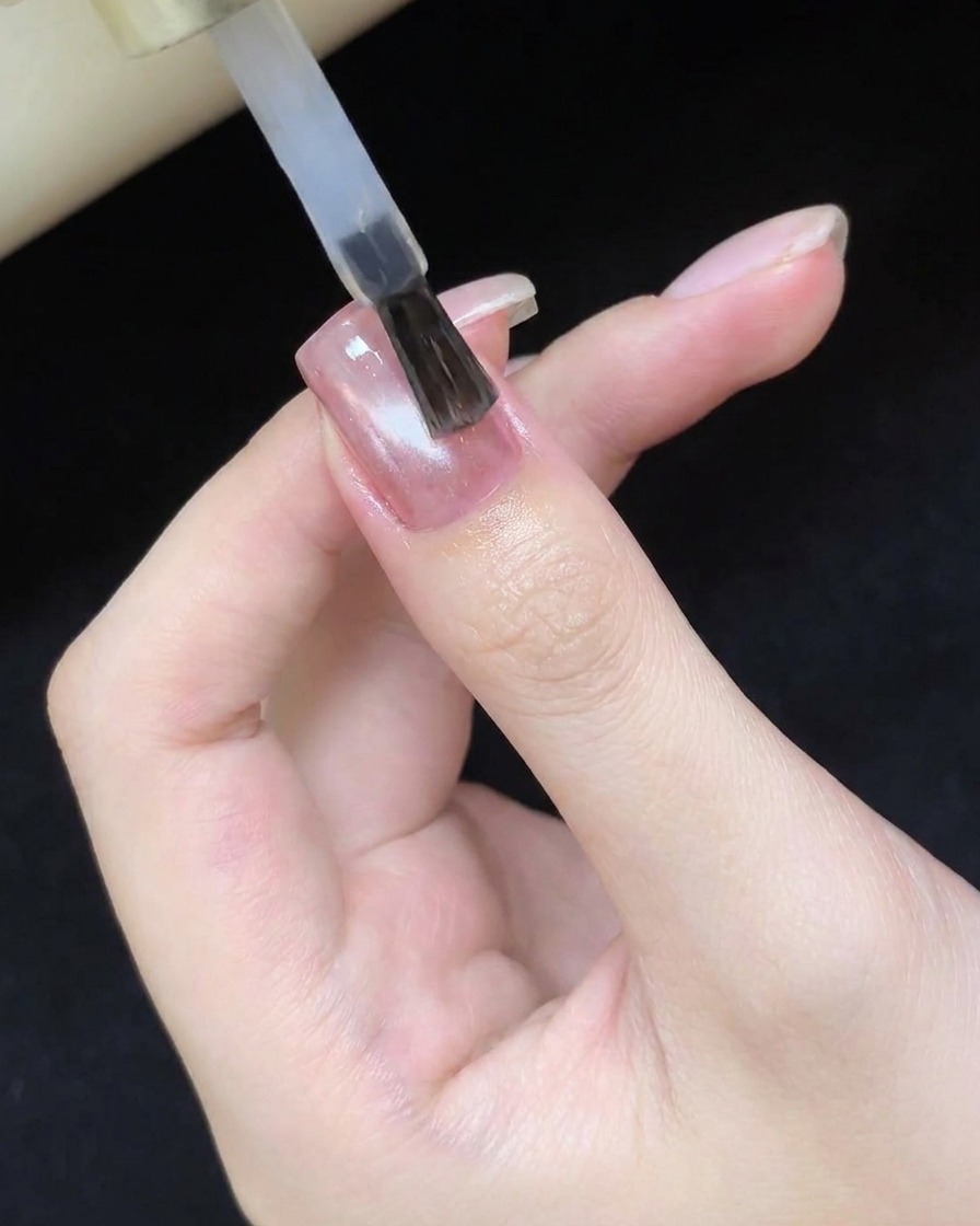 硬化したキャッツアイネイルの上にクリアトップコートを塗布している様子。