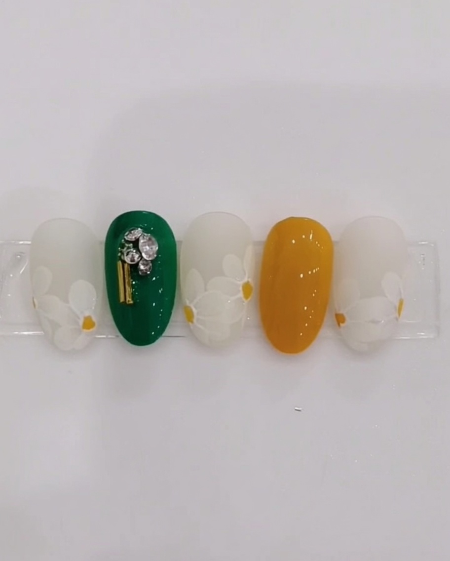 細筆を使って爪の中心にイエローのドットを置いている様子。