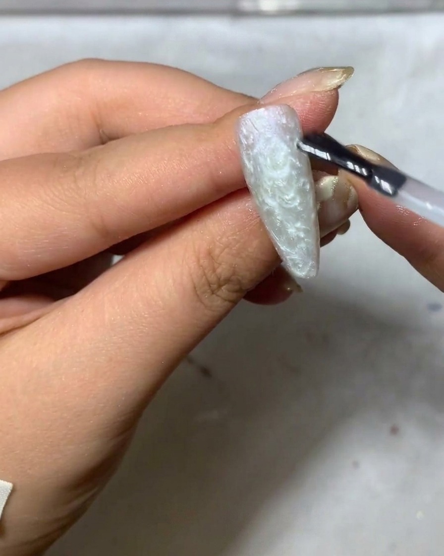 細いライナーブラシでマットなベースの上に白い花びらを描き始めている様子