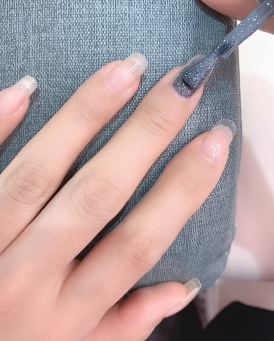 清潔な爪にライトグレーのジェルポリッシュをブラシで塗布している様子。