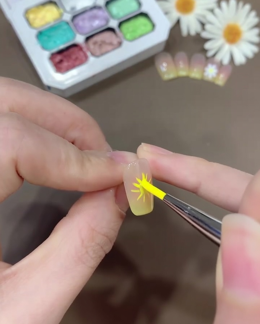 ライナーブラシで白いジェルを取り、ガイドに沿って丸みのある花びらを丁寧に描いている様子。