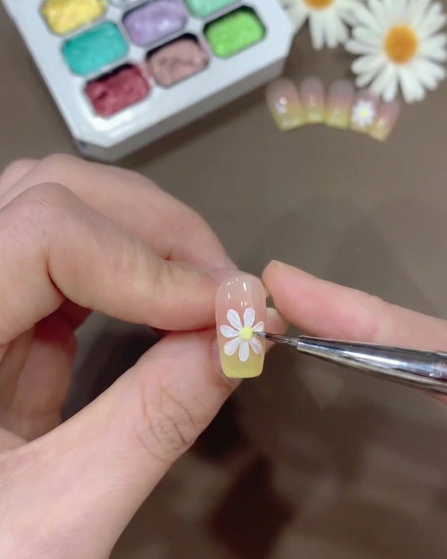 白い花びらの中央に、小さな黄色いジェルを点として加えている様子。