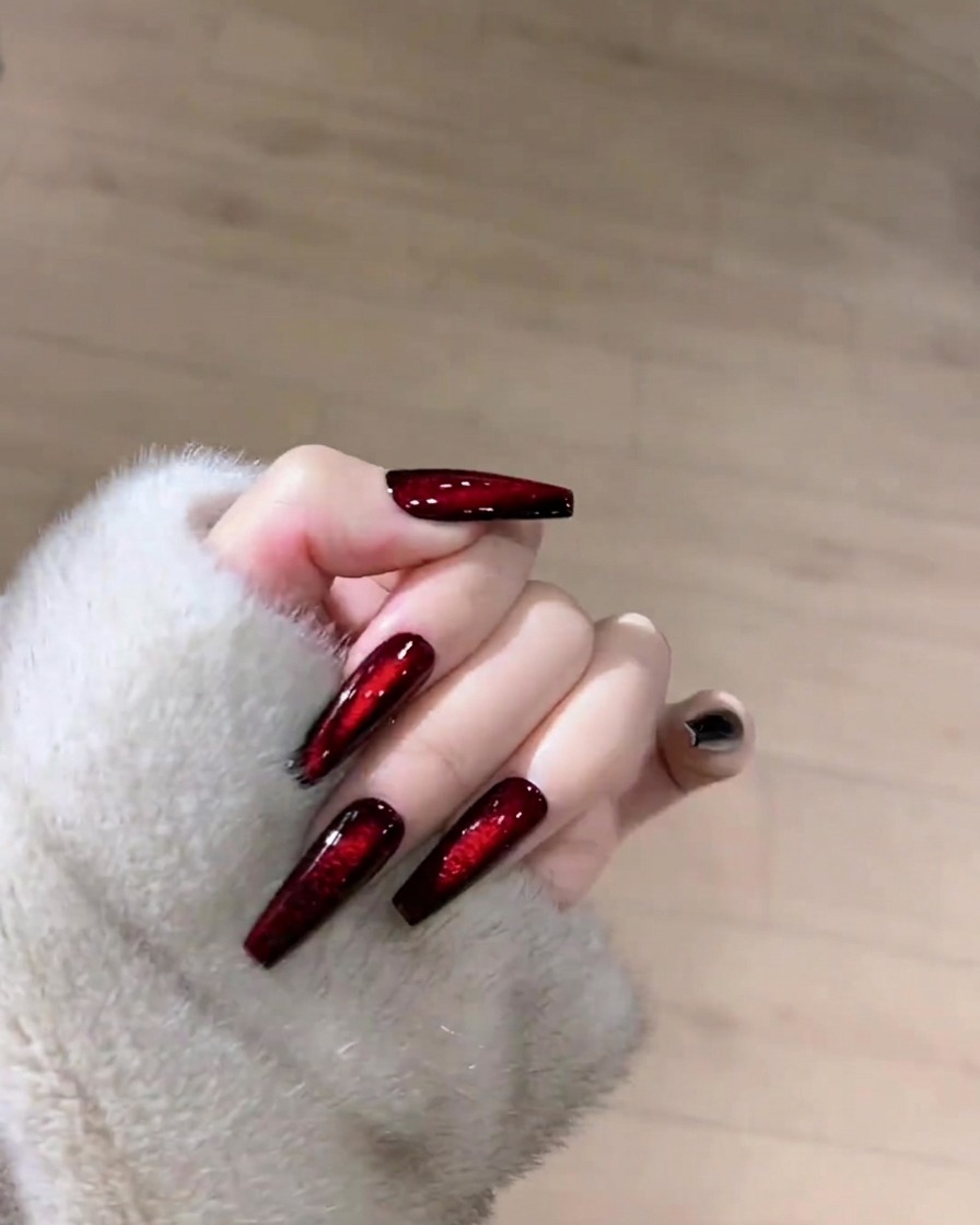ダークルビーのキャッツアイネイルの表面を、リントフリーワイプを持ってクリーニングしている様子。