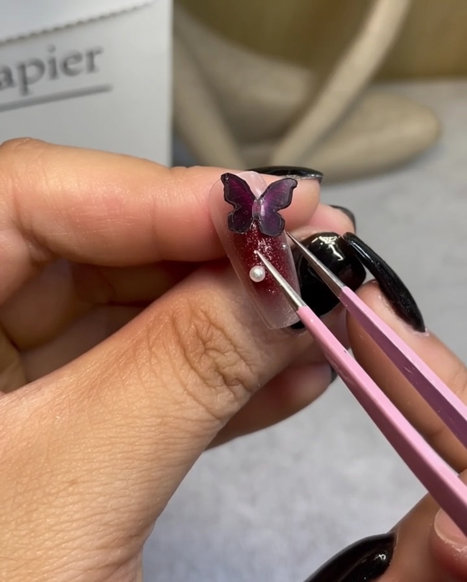 ピンセットを使い、蝶のパーツの周りに小さな白いパールを配置している様子