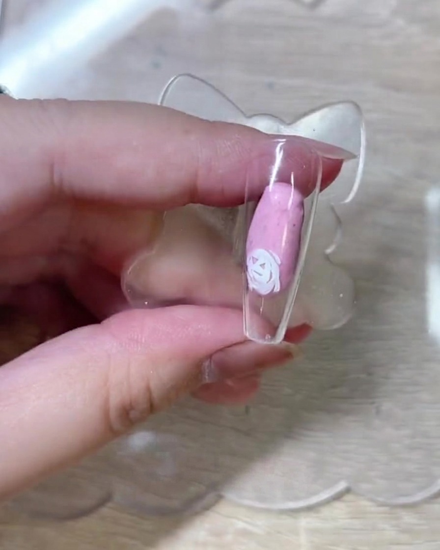 ネイルチップ上にさらに白いバラの輪郭を追加し、花の構成を作っている様子。