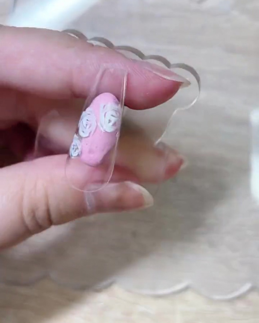 ネイルチップ全体に白いバラの花びらの輪郭がバランスよく描かれている様子。