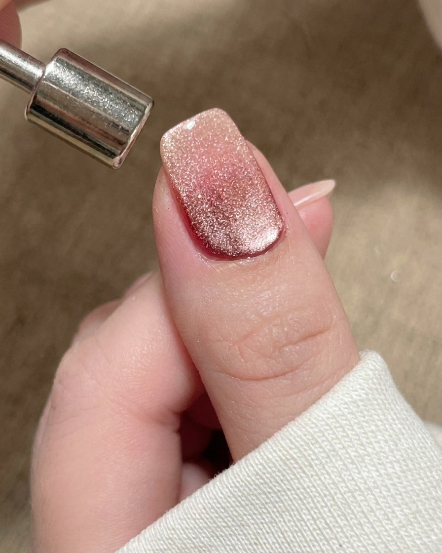 マグネットを使用して、磁気によるシマーを爪のフリーエッジに向かって押し出しているクローズアップ画像。