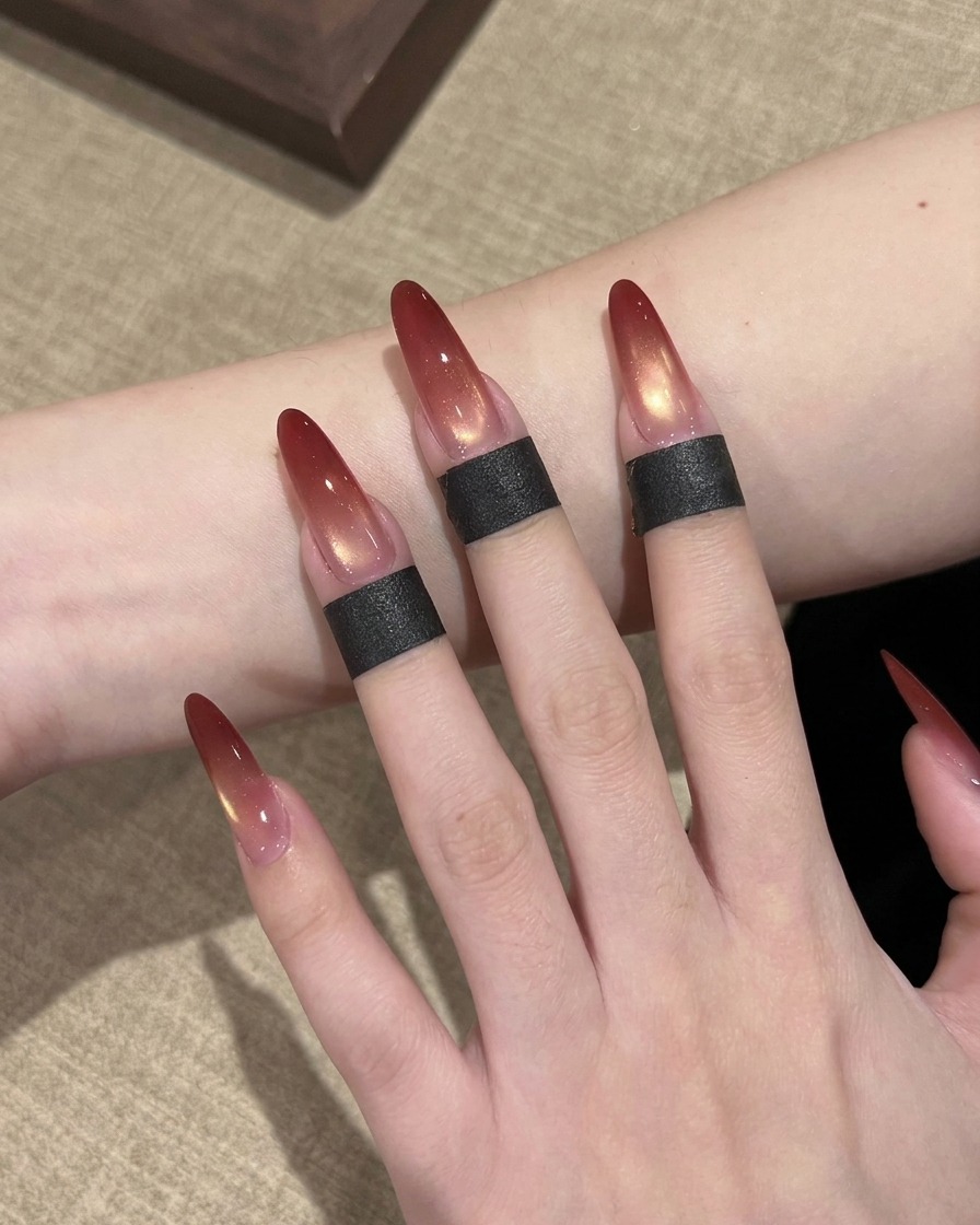 長いアーモンド型の人工爪の先端に、ネイルブラシで赤色のジェルポリッシュをちょんちょんと乗せているクローズアップ。