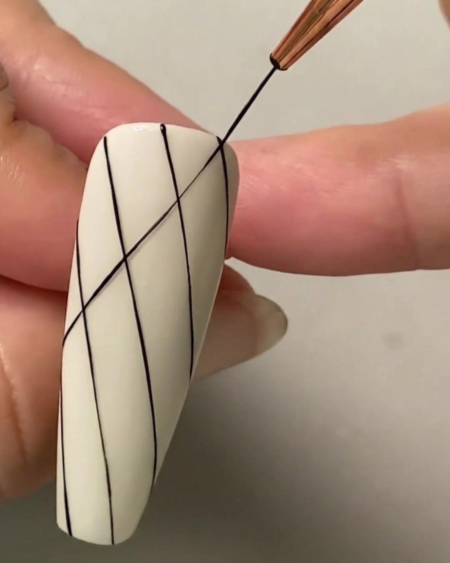 ダイヤモンドのグリッドパターンを形成するため、既存の平行線に交差する斜めの黒いラインを描いている極細ライナーブラシ。
