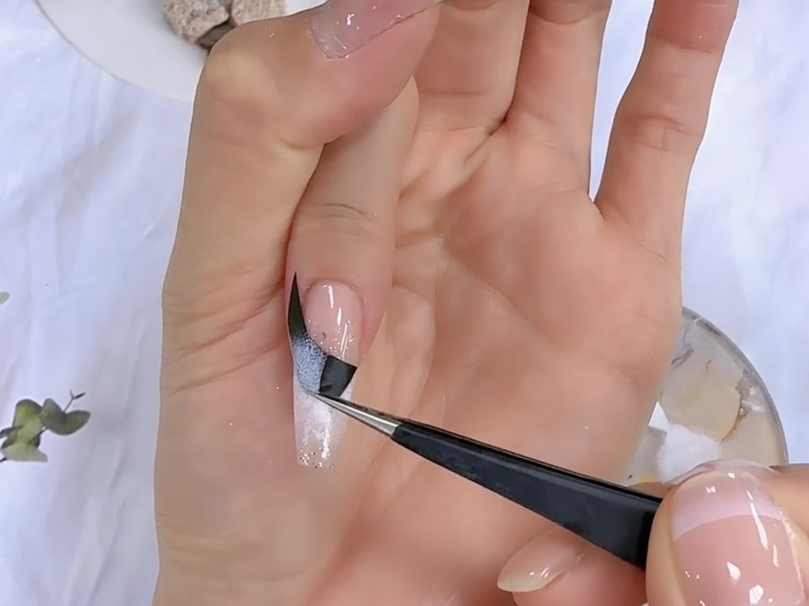 ピンセットを使って黒いフレンチガイドシールを剥がし、美しいグラデーションラインを現している様子。