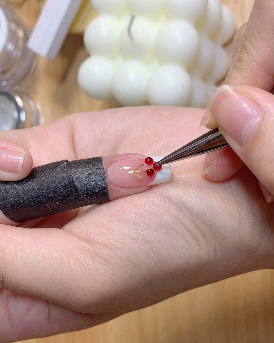 ピンセットを使って、フレンチマニキュアを施した爪の表面に2つの小さな透明な3Dジェルボールを置いている様子。