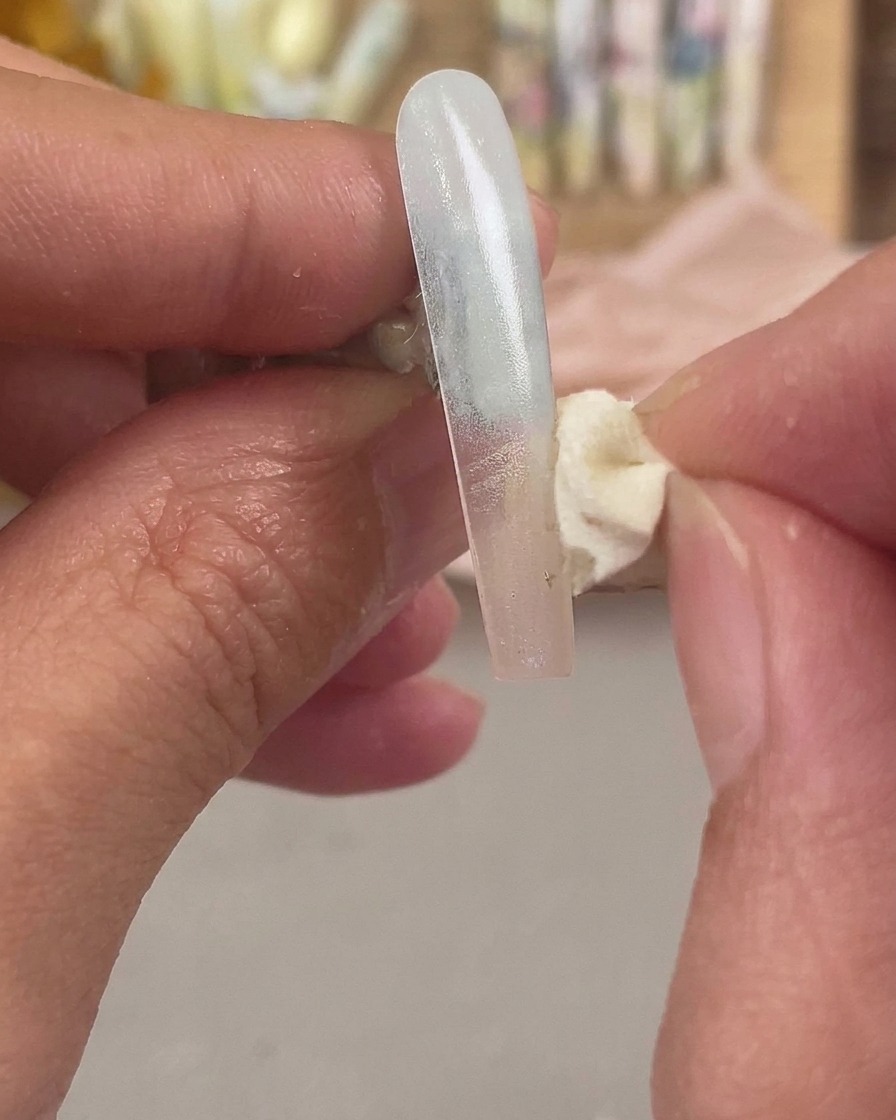 化粧用スポンジを使って、ネイルエクステンションの先端に2色目をのせ、オンブレ効果をブレンドしている様子。