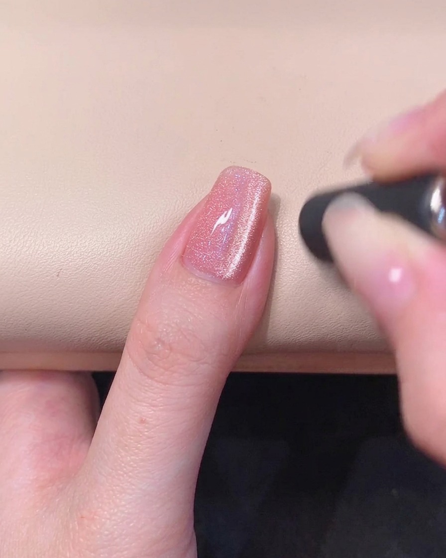 爪の中央に光り輝くキャッツアイのストライプが浮かび上がったピンクのマグネットネイル
