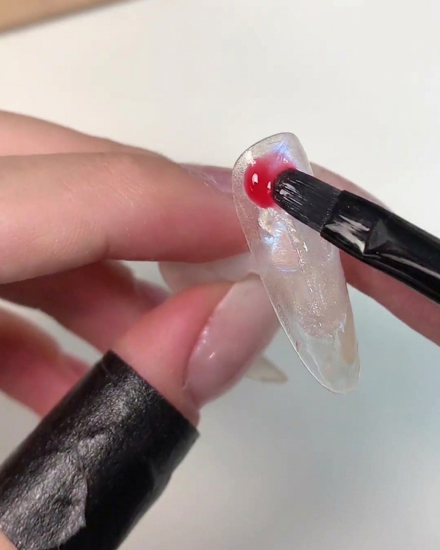 ブラシを使ってネイルアートの表面に鮮やかなカラージェルをランダムにのせている様子。