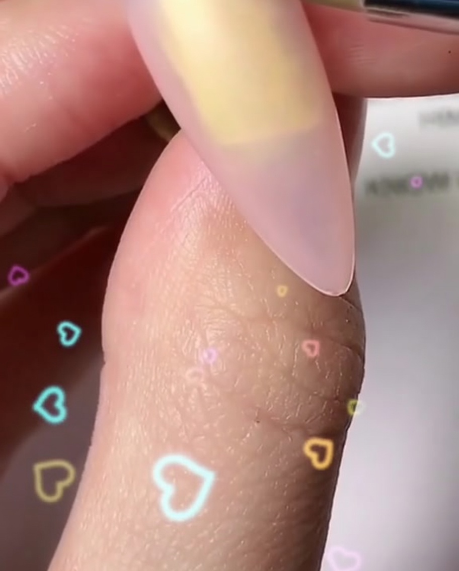 細かいブラシを使って、爪の上に丸みのある白い花びらを1枚ずつ描き、花の形を形成している様子。