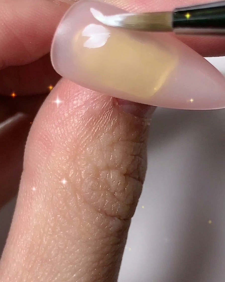ネイルブラシを使って白い花びらを加え、爪全体に複数の花のアウトラインを完成させている様子。