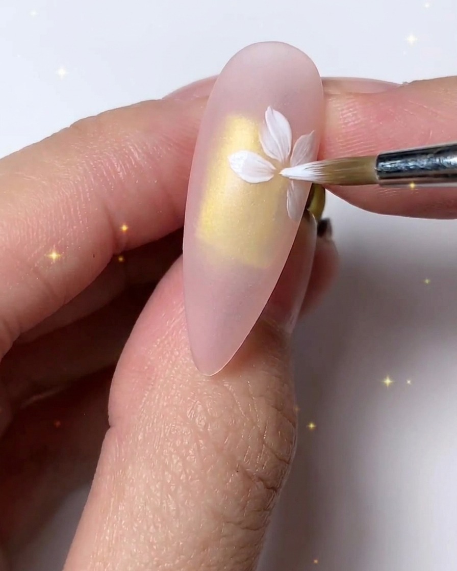 細かいブラシを使って、爪の上で繊細な見た目のために白い花びらを微調整し重ね塗りしている様子。