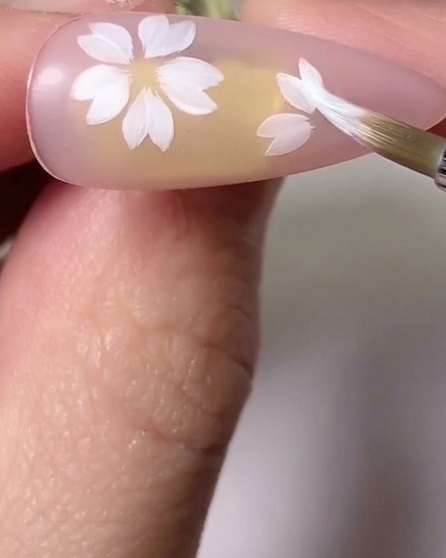 奥行きを加えるために、桜の花びらの上でピンクと白の色合いをブラシでブレンドしている様子。