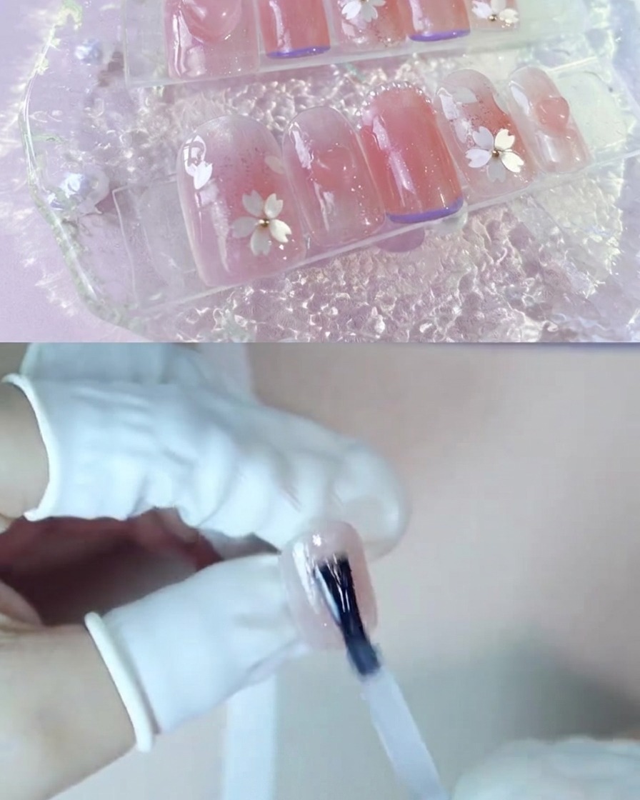 チークピンクのネイルの上に透明な補強ジェルのレイヤーを塗布している手。